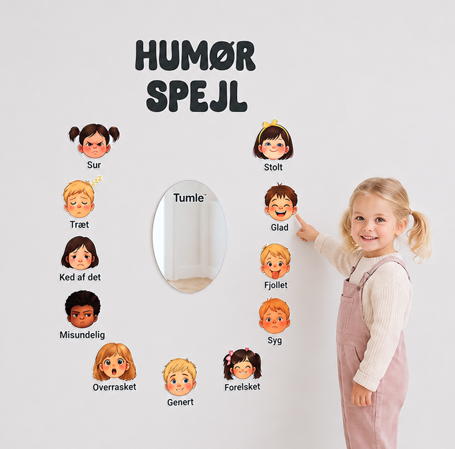 Pige peger på et følelsesansigt ved siden af TUMLE HUMØRSPEJL™ på væggen