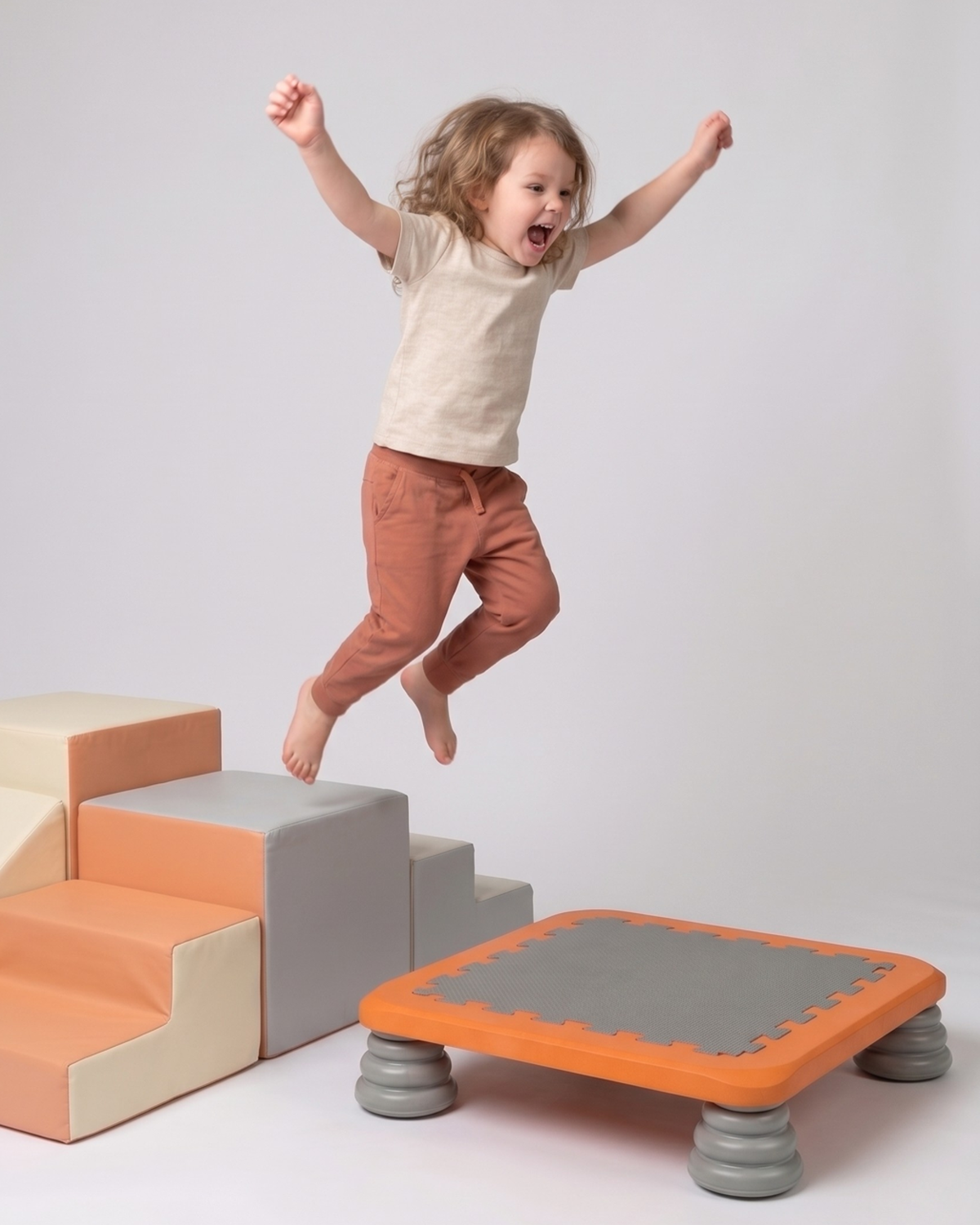 Barn hopper fra bløde skumtrin ned på TUMLE TRAMPOLIN™
