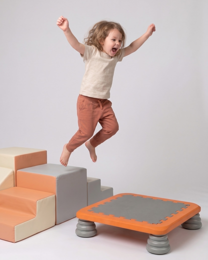Barn hopper fra bløde skumtrin ned på TUMLE TRAMPOLIN™